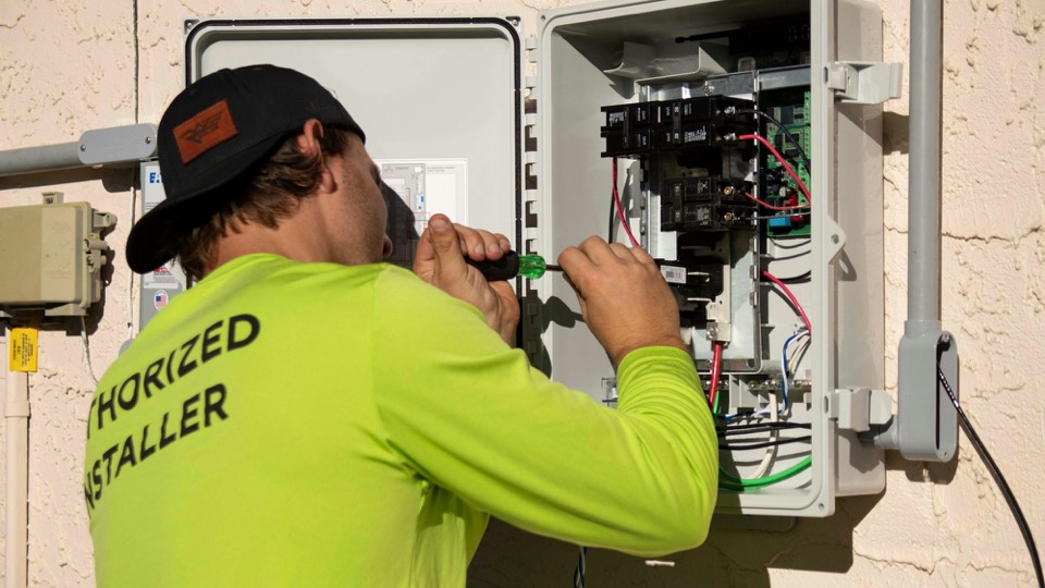 Un électricien visse un panneau électrique